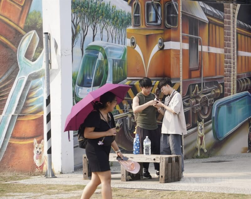 圖為民眾撐傘在高雄駁二藝術特區周邊遊憩。（中央社檔案照片）