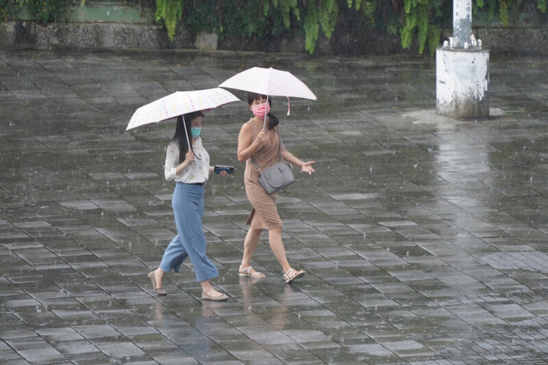 台北市大同區民眾撐傘遮雨。（中央社檔案照片）