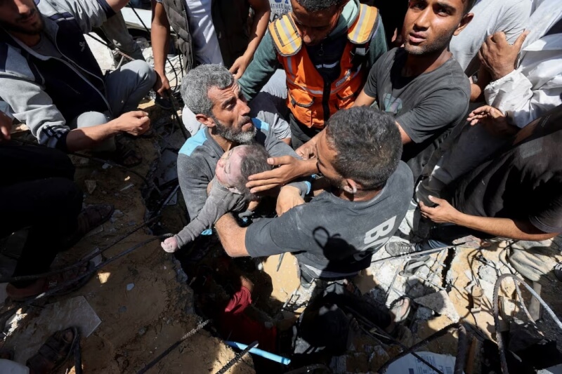 加薩走廊遭以色列襲擊，巴勒斯坦民眾14日在廢墟中搬出罹難者遺體。（路透社）
