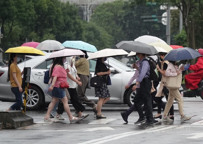 圖為民眾在台北南港展覽館附近撐傘過馬路。（中央社檔案照片）