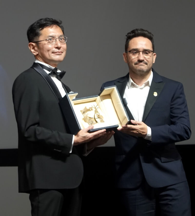 吉卜力工作室20日成為歷來第一個在法國坎城影展上獲頒榮譽金棕櫚獎殊榮的團體，宮崎駿的兒子宮崎吾朗（左）出面代表領獎。（共同社）
