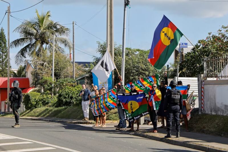 23日法國總統馬克宏車隊經過新喀里多尼亞努美阿時，民眾舉旗示威。（路透社）