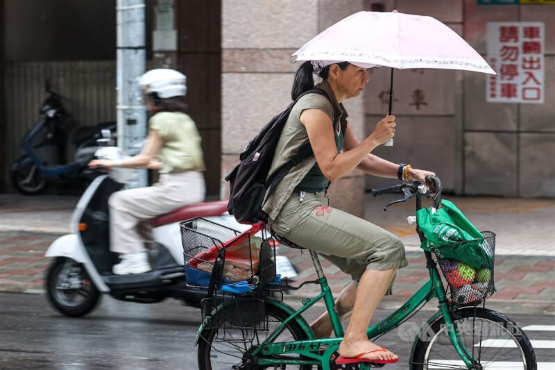 圖為北市民眾撐傘騎自行車。（中央社檔案照片）