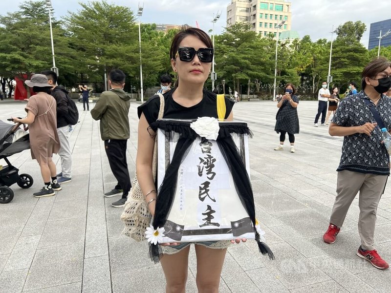 國會職權修法掀起立法院政黨攻防,28日台中市府前廣場有民眾手持「台灣民主」黑白照表示,今天立法院三讀通過法案,代表台灣民主已死,她為台灣民主作成遺照,以紀念這天。中央社記者郝雪卿攝 113年5月28日
