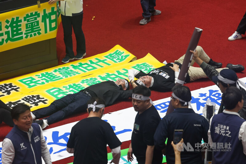 立法院會28日續審國會職權修法相關法案,各黨團立委在議場內張貼布條、標語。圖為民進黨立委李坤城(躺者左)、郭國文(躺者右)躺在地上占位。中央社記者吳家昇攝 113年5月28日