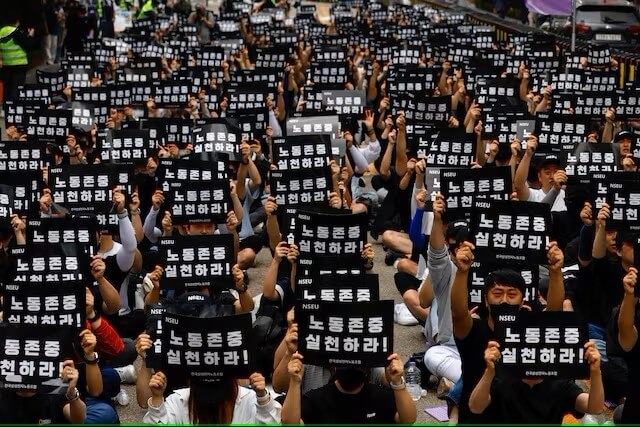 三星電子工會成員24日在首爾三星大樓前手舉「尊重勞工」標語表達訴求。（路透社）