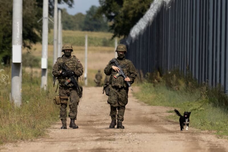 2名波蘭士兵和一隻狗2023年8月30日沿著波蘭、白俄羅斯邊境的邊境圍欄行走。（路透社）