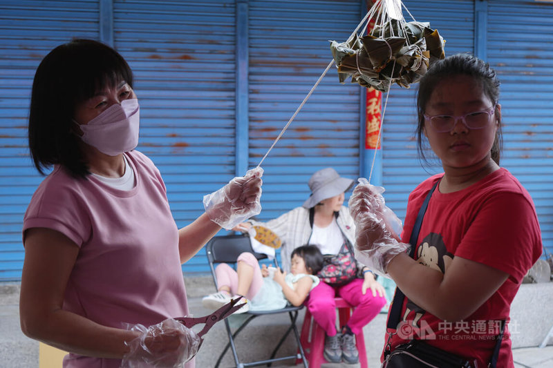 2024屏東好客米食節「百人包粽」活動1日在佳冬老街熱鬧展開,參與民眾中有不少是家長帶著下一代到場參與,傳承包粽手藝。中央社記者黃郁菁攝 113年6月1日