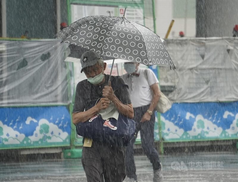 圖為5月28日高雄市三民區午後大雨，民眾撐傘過馬路。（中央社檔案照片）