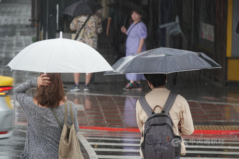 圖為台北市中山區上午大雨滂沱，民眾撐傘等待過馬路。（中央社檔案照片）