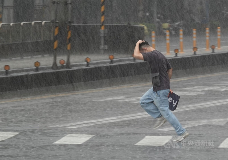 台北市中山區有民眾未攜帶雨傘出門，快速過馬路躲雨。（中央社檔案照片）