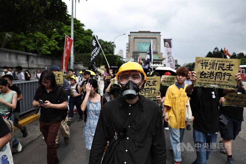在台港人及支持香港的團體9日舉行「香港自由6月 2024台北遊行—捍衛民主 台港同行」遊行，參與民眾戴著防毒面具及頭盔走上街頭，持標語表達訴求。中央社記者翁睿坤攝 113年6月9日