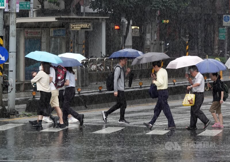 圖為台北市中山區下起傾盆大雨，民眾撐傘過馬路。（中央社檔案照片）