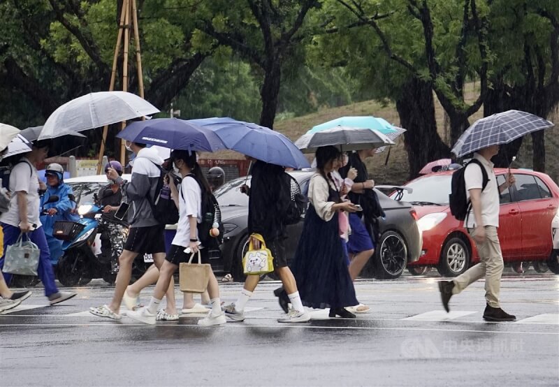 圖為高雄市新興區街頭民眾撐傘過馬路。（中央社檔案照片）