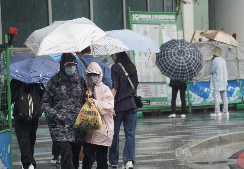 圖高雄市三民區民眾撐傘走在街頭。(中央社檔案照片)
