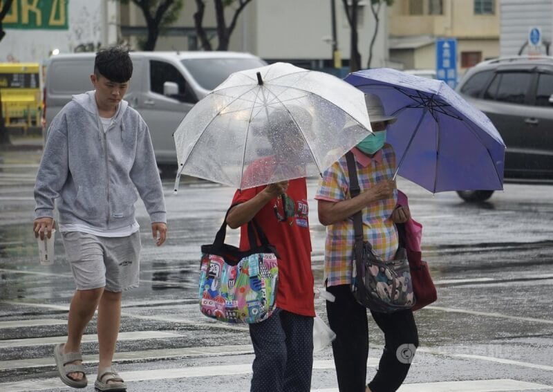 图为高雄市新兴区降雨，民众未携带雨具淋雨过马路。（中央社档案照片）