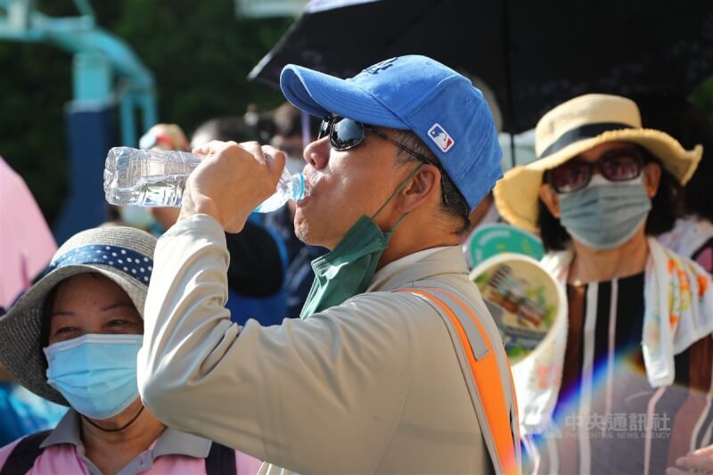 台北市北投區健行民眾在烈日下補充水分防中暑。（中央社檔案照片）