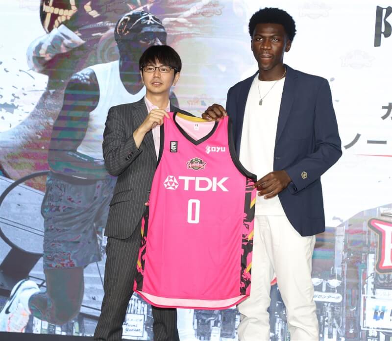 台灣職籃好手阿巴西(右)17日正式宣布加盟日本B1聯盟秋田北部喜悅,從球團主席水野勇氣(左)手中接下0號新球衣。中央社記者謝佳璋攝 113年6月17日