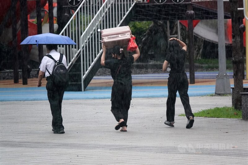 圖為台北南港車站民眾舉起行李箱擋雨。中央社記者鄭傑文攝 113年6月16日