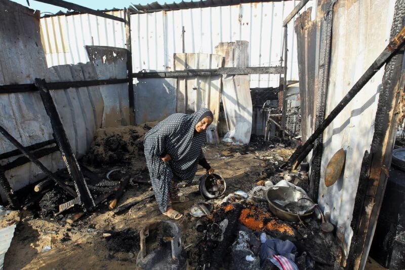 以色列轟炸加薩南部拉法市，一名巴勒斯坦婦人19日在燒毀的廢墟中撿拾物品。（路透社）