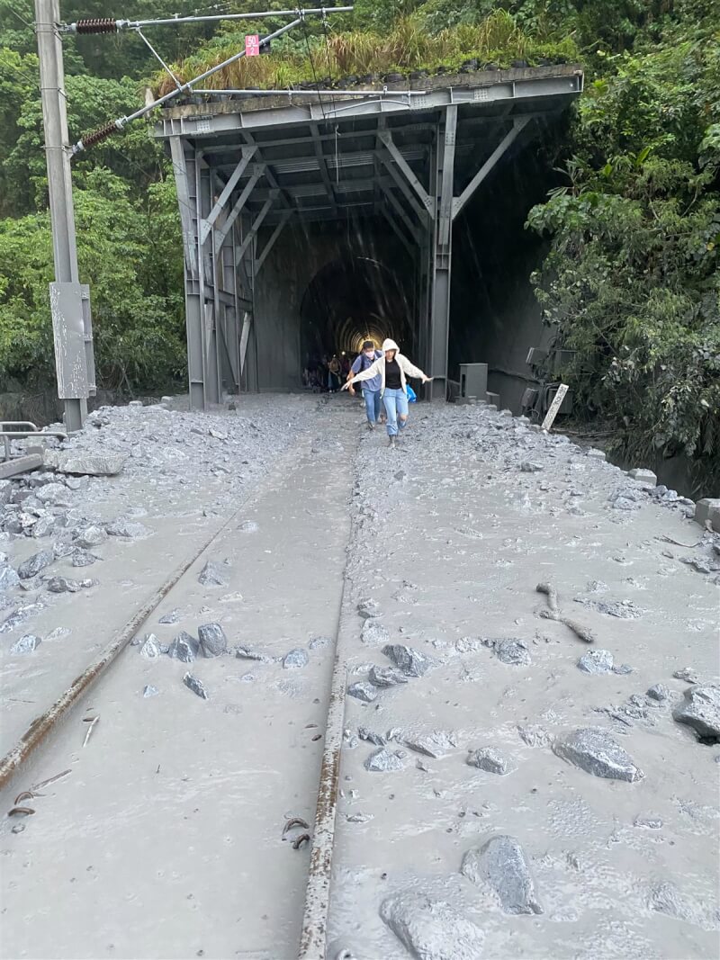 台鐵229班次EMU3000型新自強號21日下午行經花蓮和仁路段時疑撞上落石，列車緊急停靠在清水隧道內，目前已知司機員手骨折、多人輕傷。圖為乘客下車走過布滿土石泥濘的鐵軌。（民眾提供）中央社記者張祈花蓮傳真 113年6月21日