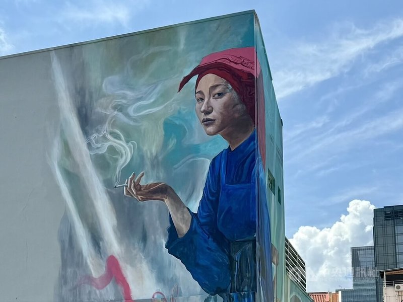 在新加坡牛車水，由美國藝術家鄧斯頓（Sean Dunston）所繪的壁畫展示一名綁著紅頭巾的年輕女子手拿香菸，近日引發討論、成為媒體報導焦點。中央社記者吳昇鴻新加坡攝  113年6月25日