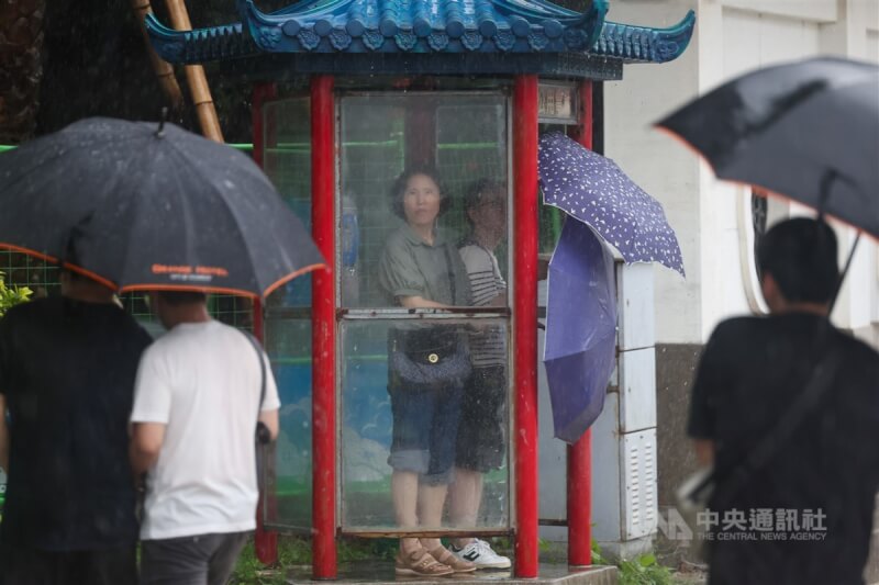 24日中正區午後下起滂沱大雨，遊客到電話亭內躲雨。中央社記者吳家昇攝 113年6月24日
