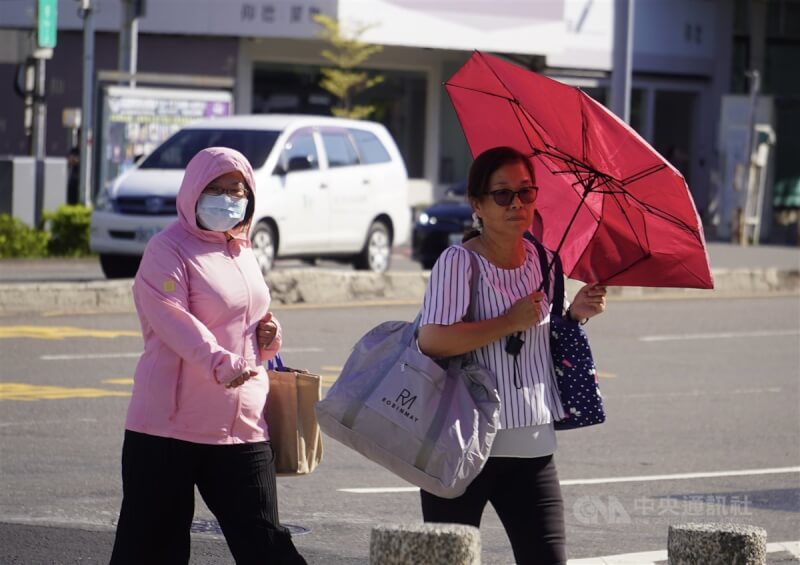 圖為民眾在高雄市新興區撐傘、戴帽子遮陽過馬路。（中央社檔案照片）