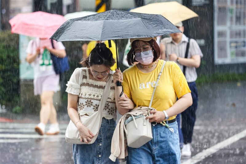 圖為24日北市午後大雨，信義區街頭民眾共撐一把傘快步通過馬路。（中央社檔案照片）