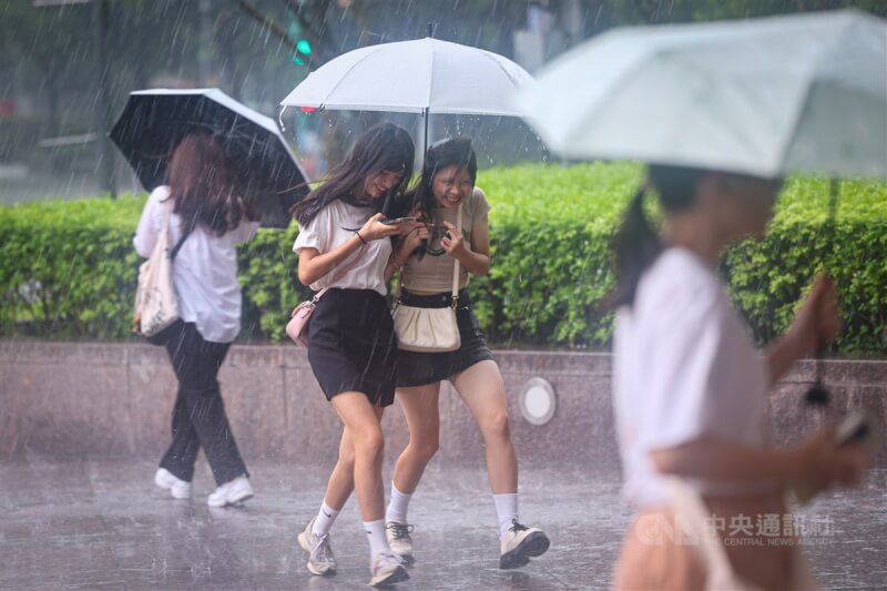 台北市信義區午後下起大雷雨，民眾撐傘快步躲雨。（中央社檔案照片）