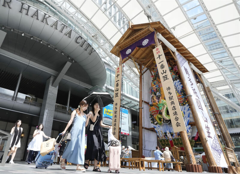 圖為日本民眾在博多車站前撐傘遮陽。（共同社）