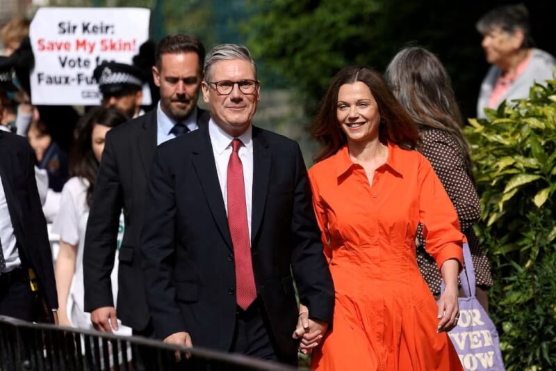 英國在野黨工黨領袖施凱爾（前左）和妻子（前右）4日走出投票站。（路透社）