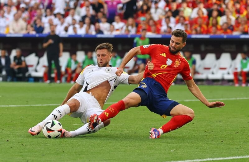 西班牙5日在歐洲國家盃足球8強賽以2比1踢走地主德國。圖為西班牙球員納喬（紅衣）與德國球員菲爾克魯格（白衣）爭球。（路透社）