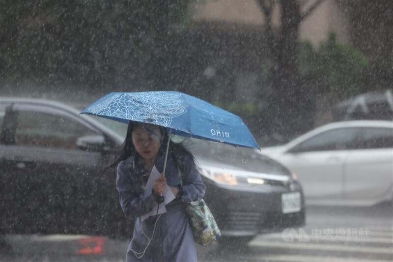 圖為台北市中正區午後雷陣雨，民眾撐傘過馬路。（中央社檔案照片）