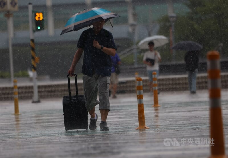 圖為1日台北松山機場一帶午後出現雨勢，民眾撐著傘、手拉行李箱過馬路。中央社記者趙世勳攝 113年7月1日