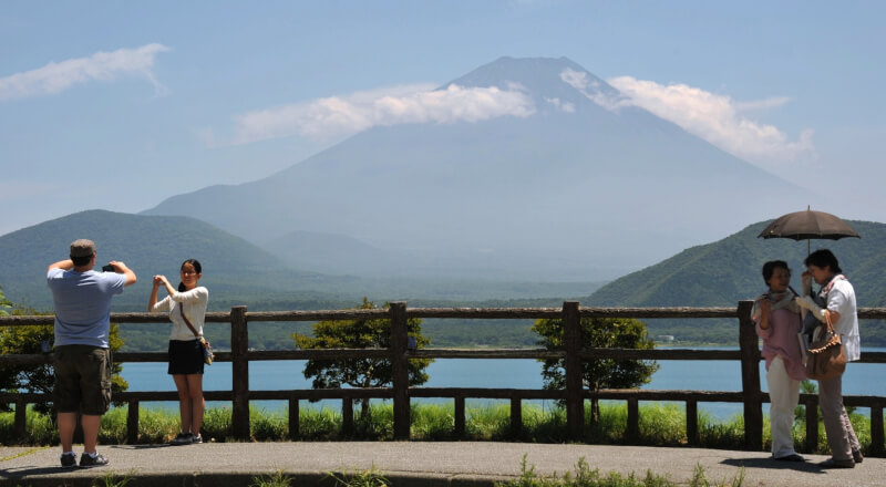 遊客在日本山梨縣本栖湖畔和富士山合影。（共同社）