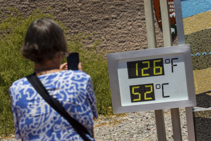 熱浪持續肆虐，美西部分地區氣溫攀升至危險程度。圖為一名女子在死谷國家公園拍攝溫度計，溫度計顯示當地溫度飆到攝氏52度。（美聯社）