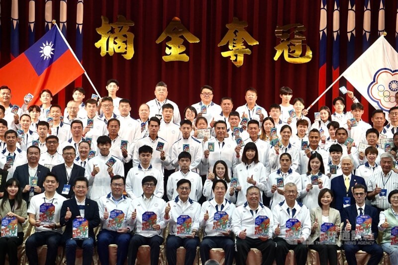 總統賴清德(前右6)9日南下高雄國家運動訓練中心,出席2024巴黎奧運台灣代表團授旗典禮,與代表團一同拿著平安御守合影。中央社記者董俊志攝 113年7月9日