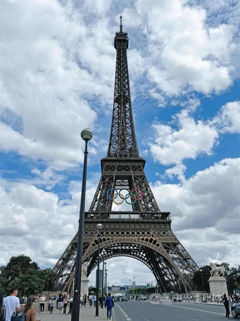 2024巴黎奧運在很多地方都寫下奧運史上獨特的一頁，也展露巴黎的浪漫基因。掛上奧運五環艾菲爾鐵塔腳下的戰神廣場屆時將成為射箭等賽事場地，7月初已封閉施工。鐵塔周邊人潮仍絡繹不絕。中央社記者曾婷瑄巴黎攝 113年7月10日
