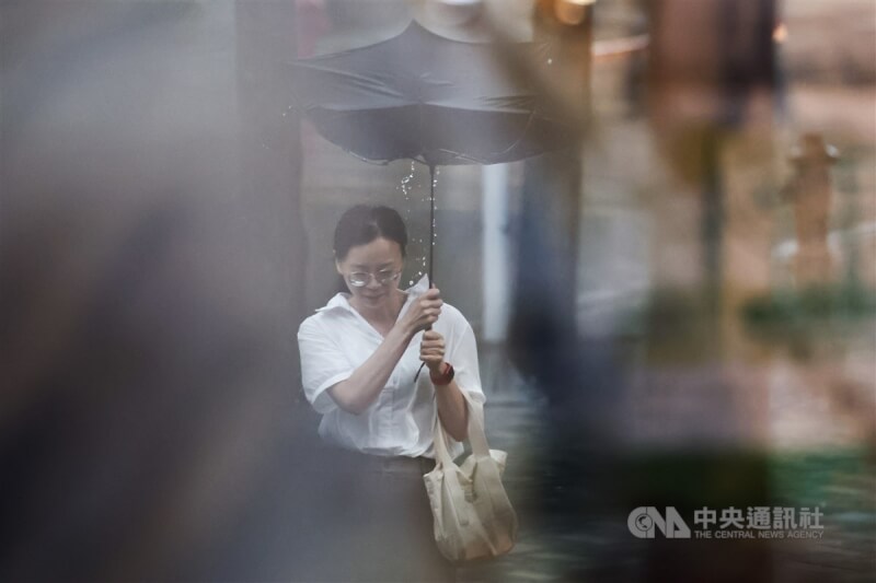 台北市內湖區民眾撐傘遇強風，導致傘面變形、雨水滴落。中央社記者翁睿坤攝 113年7月10日