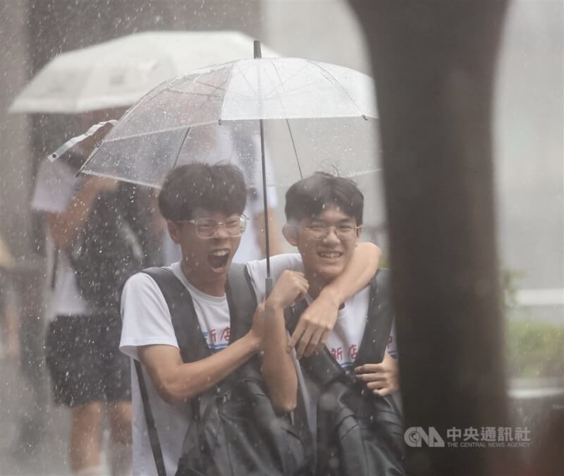 台北市大雷雨，2名學生共撐一把傘走在公館商圈街頭。（中央社檔案照片）