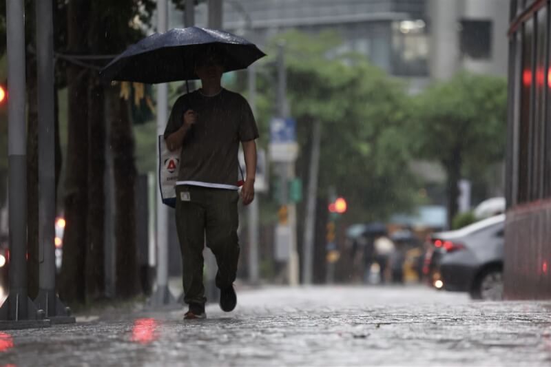 圖為台北市內湖區民眾撐傘遮雨。（中央社檔案照片）