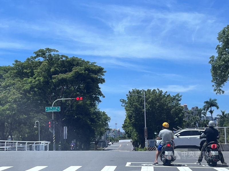 夏季酷熱，機車騎士停紅燈常躲樹蔭下，高雄市交通局7月起中午時段逐步調整縮短部分號誌週期秒數，減少停等時間。中央社記者林巧璉攝  113年7月12日