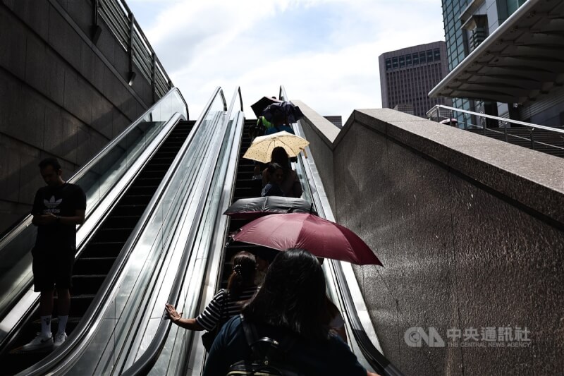 圖為台北市信義區民眾搭手扶梯，撐傘遮擋豔陽。中央社記者翁睿坤攝 113年7月15日