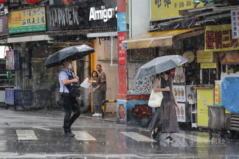 台北市松山區行人撐傘在雨中穿梭。（中央社檔案照片）