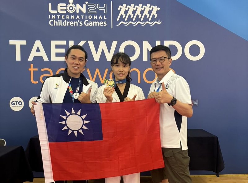 新北市在2024國際少年運動會成績亮眼,其中永和國中林立羽(中)一舉奪得跆拳道女子59公斤級金牌,頒獎後開心與市府副秘書長張其強(右)、教練楊雋希(左)持國旗合影。(新北市體育局提供)中央社記者黃旭昇新北市傳真 113年7月20日