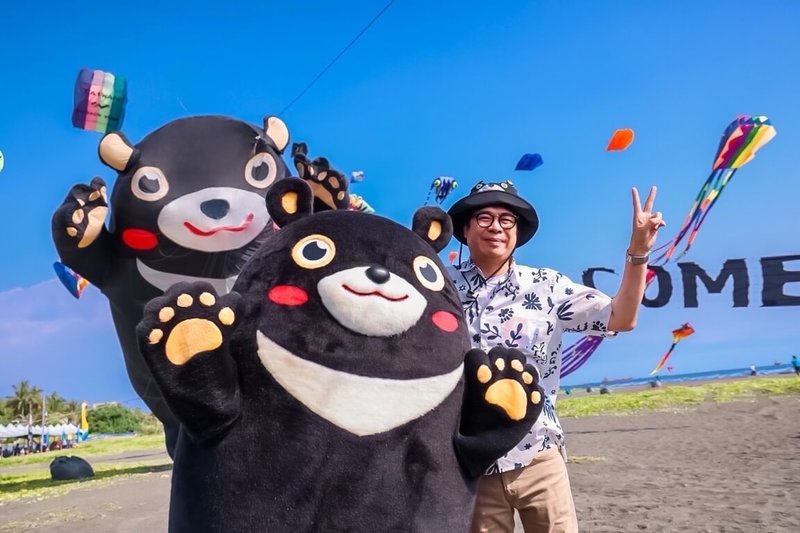 高雄市長陳其邁（圖）20日下午以一身輕鬆舒服的裝扮，化身海灘型男出席2024旗津風箏節活動，在巨大的高雄熊主題風箏前親自示範如何拍美照。（高雄市觀光局提供）中央社記者林巧璉傳真  113年7月20日