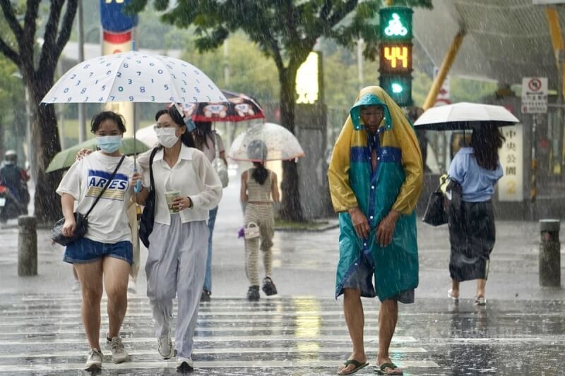 圖為高雄市新興區傍晚雨勢明顯，民眾撐傘、穿雨衣過馬路。中央社記者董俊志攝 113年7月23日