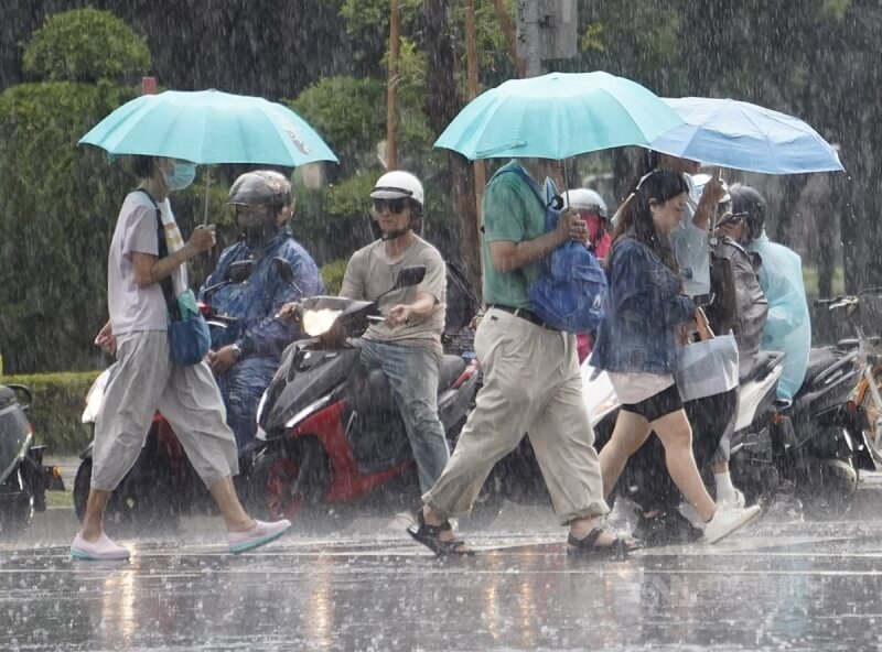 高雄市新興區民眾傍晚撐傘過馬路。中央社記者董俊志攝 113年7月23日