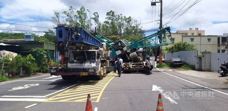 1輛載運吊車的拖板車23日上午行經林口區粉寮路二段準備轉彎時，載運吊車突然滑落並橫躺路面，警方實施雙向交通管制，並通知吊車到場排除狀況。（翻攝照片）中央社記者高華謙傳真 113年7月23日